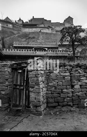 Mur de pierre avec les entrées de maisons grotte en remontant la colline à Lijiashan village, province de Shanxi, Chine Banque D'Images