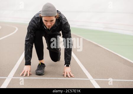 Un sportif jeune et attrayant, concentré, se prépare à courir sur l'hippodrome du stade Banque D'Images