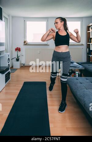 Europe, Allemagne, Rosenheim, Jeune Femme fait de l'entraînement sportif à domicile, Livingroom Banque D'Images