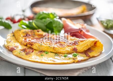 Omelette aux pois prosciutto tomates basilic et herbes sur plaque blanche Banque D'Images