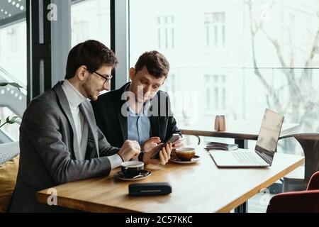 Deux hommes d'affaires parlent de nouvelles opportunités assis avec un ordinateur portable au bureau, projet de planification, compte tenu de l'offre d'affaires Banque D'Images
