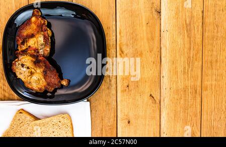 Côtelettes de porc aux condiments sur une plaque noire, sur une table en bois, la viande pour barbecue, vue de dessus, copiez l'espace, concept de barbecue Banque D'Images