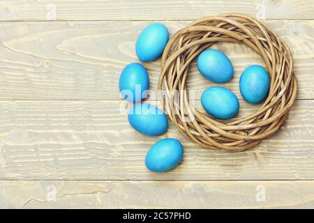 ensemble d'œufs traditionnels peints en bleu à l'intérieur de la couronne en bois tissé sur fond gris vintage. Concept joyeuses Pâques
