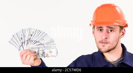 Le constructeur gagne de l'argent, le réparateur conserve de l'argent, le ventilateur fait de billets en main. L'homme en casque a obtenu un salaire, de l'argent pour le travail. Beau-homme avec un visage strict dans un casque sur fond blanc. Concept immobilier. Banque D'Images