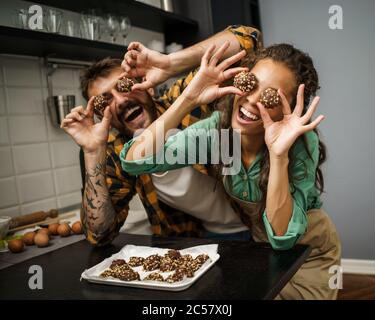 Un couple multiethnique heureux a fait des biscuits dans sa cuisine. Banque D'Images