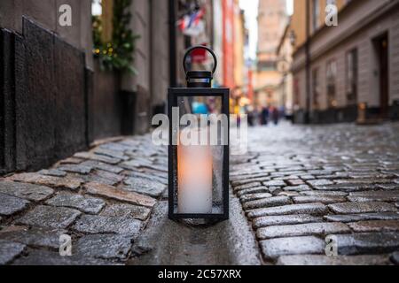 Une lanterne avec une bougie lumineuse repose sur un coin de rue pavé à Gamla stan, la vieille ville de Stockholm, en Suède. Banque D'Images