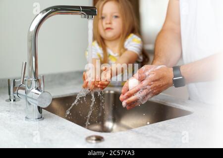 Père et fille se lavant les mains au-dessus de l'évier dans une cuisine Banque D'Images