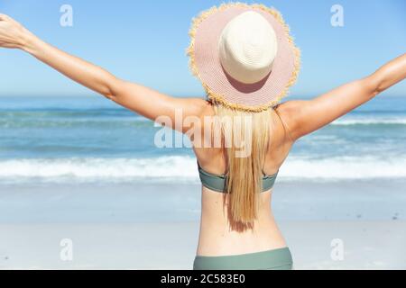 Vue arrière de la femme debout avec ses bras ouverts sur la plage Banque D'Images