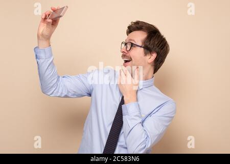 homme en chemise tenant un téléphone portable et faisant la photo de lui-même. Banque D'Images