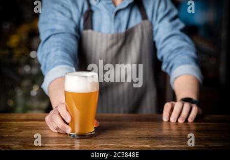 Boisson artisanale au bar. Bartender donne un verre de bière légère avec de la mousse Banque D'Images