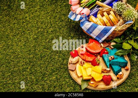 Concept pique-nique. Assortiment de fromages hollandais durs multicolores. Pesto bleu et rouge, gouda vieilli. Fraise, chocolat, noix, herbes, jus et vin. Osier b Banque D'Images