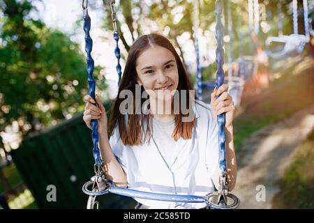 Joyeux enfant adolescente de la chaîne d'équitation balançoire au parc d'attractions