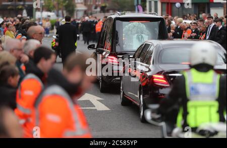 Les membres du Service de secours communautaire (en vestes haute visibilité) forment une garde d'honneur alors que le cortège funéraire de Noah Donohoe, 14 ans, quitte son école, le collège St Malachy à Belfast, où il s'est arrêté pendant un court moment flanqué de ses camarades de classe, Après ses funérailles privées à l'église Saint Patrick. Banque D'Images