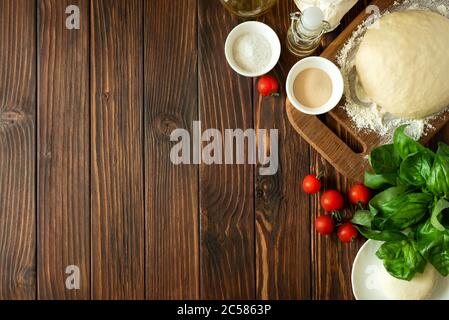 Cuisine rurale. Pâte et ingrédients pour cuire des pizzas sur une table en bois brun vintage. Vue de dessus. Arrière-plan rustique Banque D'Images