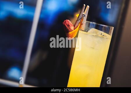 Magnifique cocktail d'alcool jaune dans des verres de vin près de la fenêtre dans le bar. Boisson décorée de roses sèches et d'orange. Boisson pour femmes. Banque D'Images