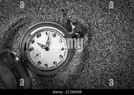 Une vieille montre de poche dans le sable. L'horloge est tombée dans le sable. Le temps est écoulé. Durée de fonctionnement. Temps de fuite. Banque D'Images