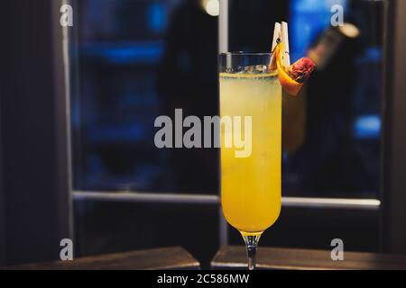 Magnifique cocktail d'alcool jaune dans des verres de vin près de la fenêtre dans le bar. Boisson décorée de roses sèches et d'orange. Boisson pour femmes. Banque D'Images