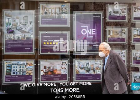 Un homme portant un masque facial de protection passe devant une fenêtre d'agents immobiliers à Knightsbridge, Londres, alors que la croissance annuelle des prix de l'immobilier s'est arrêtée en juin, avec une baisse de 0.1% de la valeur de l'immobilier d'une année sur l'autre, selon la société du bâtiment nationale. Banque D'Images