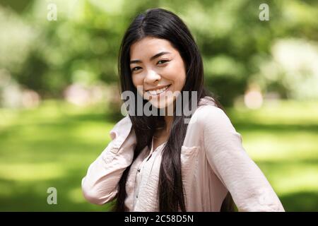 Portrait de la belle fille asiatique heureuse posant dans le parc d'été Banque D'Images