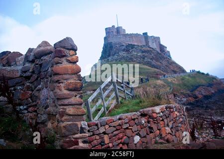 Mur en pierre et clôture en bois menant à Lindisfarne, sur l'île Sainte, située à l'arrière-plan proche. Banque D'Images