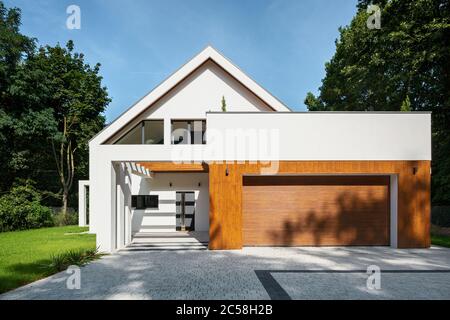 Élégante maison blanche avec façade en bois sur garage et allée pavée Banque D'Images