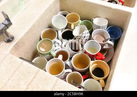Pile sale de tasses et de mugs non lavés dans le lavabo du garde-manger Banque D'Images