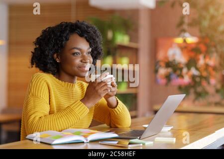 Dreamy african girl Dencking thé tout en recherchant un emploi en ligne Banque D'Images