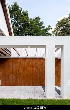 Vue extérieure de la maison moderne avec élévation blanche, éléments en bois et piliers Banque D'Images