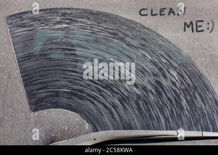 l'inscription clean me sur la lunette arrière d'une voiture sale dans une couche de poussière et de saleté sèche, vue rapprochée d'un véhicule sale arrière. Banque D'Images