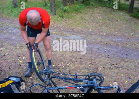 Réparation roue de bicyclette, l'homme percé roue de bicyclette, le trou de roue de bicyclette, forêt, région de Kaliningrad, Russie, Europe de l'Est, le 31 juillet 2019 Banque D'Images