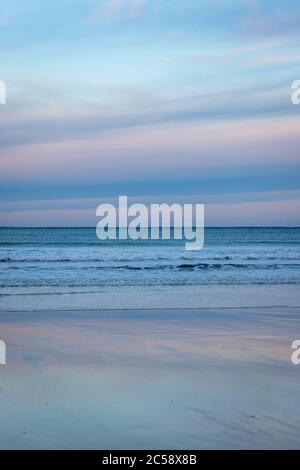 Admirez l'horizon lointain sur les vagues ondulantes avec un coucher de soleil aux couleurs vives et éclatantes qui se reflète sur une plage de sable humide et scintillante, en Écosse Banque D'Images