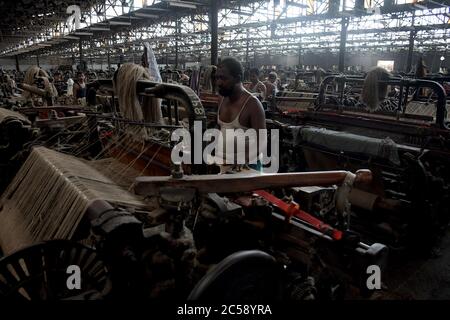 DHAKA, BANGLADESH - 01JULY 2020: Travailleurs qui travaillent à la fabrication de sacs de jute dans l'usine de traitement de jute de Narayanganj, près de Dhaka. L'industrie du jute au Bangladesh est une industrie qui revêt une importance historique et culturelle et qui était autrefois la plus grande industrie de la région. Banque D'Images