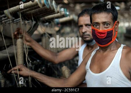 DHAKA, BANGLADESH - 01JULY 2020: Travailleurs qui travaillent à la fabrication de sacs de jute dans l'usine de traitement de jute de Narayanganj, près de Dhaka. L'industrie du jute au Bangladesh est une industrie qui revêt une importance historique et culturelle et qui était autrefois la plus grande industrie de la région. Banque D'Images