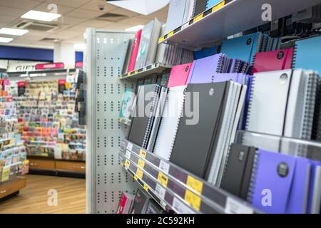 Sélection colorée de tailles et de styles variés de carnets et autres produits fixes vus sur les tablettes inférieures d'une librairie bien connue. Banque D'Images