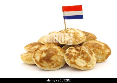 Mini crêpes hollandaises fraîchement cuites appelées « poffertjes » avec un toque de drapeau hollandais sur fond blanc Banque D'Images