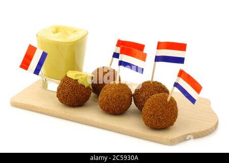 Un véritable en-cas traditionnel hollandais appelé « bitterballen » avec un topic à dents drapeau hollandais sur un panneau de découpe en bois sur fond blanc Banque D'Images