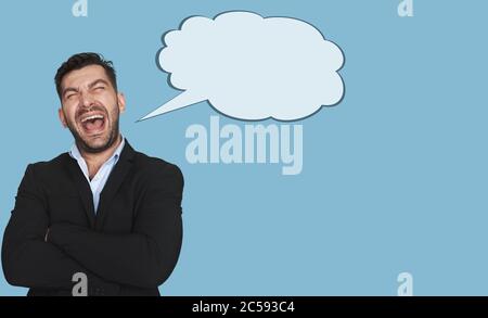 Jeune homme à barbe, très attrayant, chantant à voix haute tout en se tenant isolé sur fond bleu de studio Banque D'Images