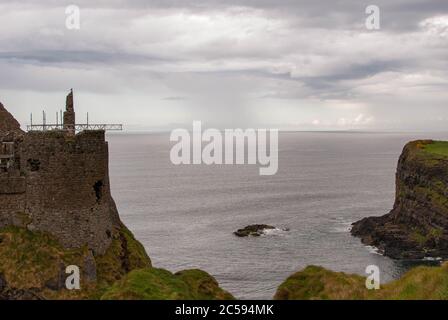 Le château de Dunluce est entouré de la mer, de rochers et de journées nuageuses avec de la pluie sur son chemin. Banque D'Images