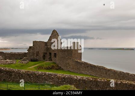 Le château de Dunluce est entouré de la mer, de rochers et de journées nuageuses avec de la pluie sur son chemin. Banque D'Images
