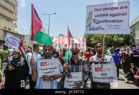 Les Palestiniens affichent des plaques et lèvent leur drapeau national lors de la protestation contre le projet d'Israël d'annexer des parties de la Cisjordanie occupée, à Gaza.les attentes d'une annonce israélienne majeure sur les annexions controversées en Cisjordanie occupée se sont estompées, Alors que la critique mondiale du projet s'est montée et que les manifestants palestiniens ont commencé à se rassembler à Gaza. Banque D'Images