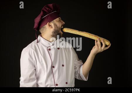 Beau barbu chef homme en uniforme bouchées baguette, cuisinier boulanger mâle Banque D'Images