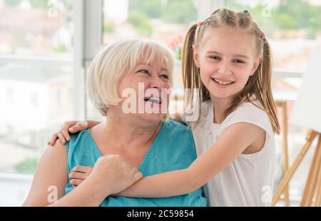 Portrait d'une grand-mère heureuse embrassant avec une petite-fille à l'intérieur Banque D'Images