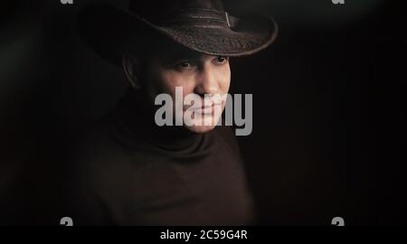 homme portant un chapeau de cow-boy sur fond noir de studio Banque D'Images