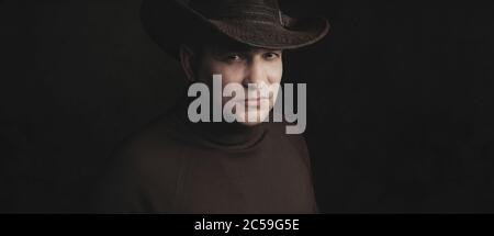 homme portant un chapeau de cow-boy sur fond noir de studio Banque D'Images