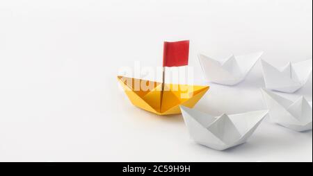 Concept de leadership. Drapeau rouge Origami bateau à papier jaune (navire) menant les autres bateaux blancs. Un navire leader dirige d'autres navires. Banque D'Images
