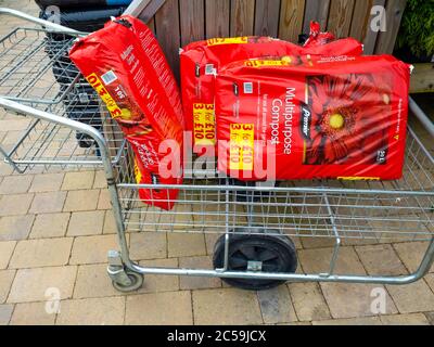 Trois sacs rouges de compost multi-usage dans un centre de jardin dans un chariot à trois prix pour £10 Banque D'Images