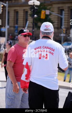 Ottawa, Canada. 1er juillet 2020. La foule de quelques centaines de personnes se sont ralliées devant le Parlement canadien le jour du Canada pour montrer leur mécontentement à l'égard du gouvernement Trudeau. Un manifestant avec un « Make Canada de nouveau » parlant avec un participant. Les plaintes allaient de divers sujets mais surtout de la crise actuelle de Covid 19. Credit: Meanderingemu/Alamy Live News Banque D'Images