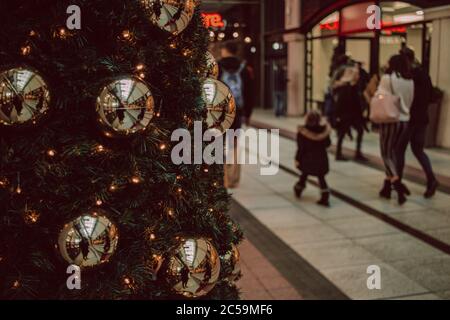 Les clients qui marchent devant un arbre de Noël dans un centre commercial ou un centre commercial, Gunwharf Quays, Portsmouth, Royaume-Uni Banque D'Images