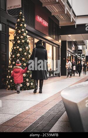 Les clients qui marchent devant un arbre de Noël dans un centre commercial ou un centre commercial, Gunwharf Quays, Portsmouth, Royaume-Uni Banque D'Images