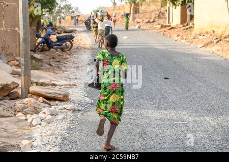 Afrique, Afrique de l'Ouest, Bénin, Natitinqou. Une jeune fille africaine qui court sur la route. Banque D'Images